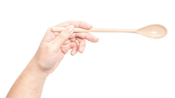 istock Female hand holding a brown plastic spoon isolated on white background. 2168484840