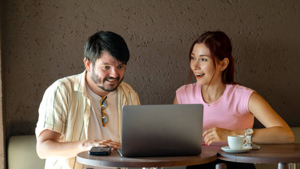 istock A young man and a young woman, both business professionals, are happily working on their laptops at a café outside the office on a summer day 2168487607
