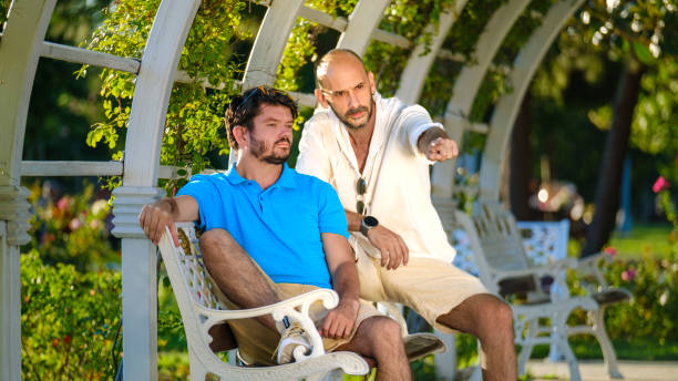 Two charismatic middle-aged businessmen, friends, enjoying a pleasant time together in a beautiful park after work