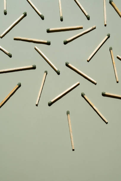 istock Wooden matchsticks with green tips scattered on light green surface. 2168489773