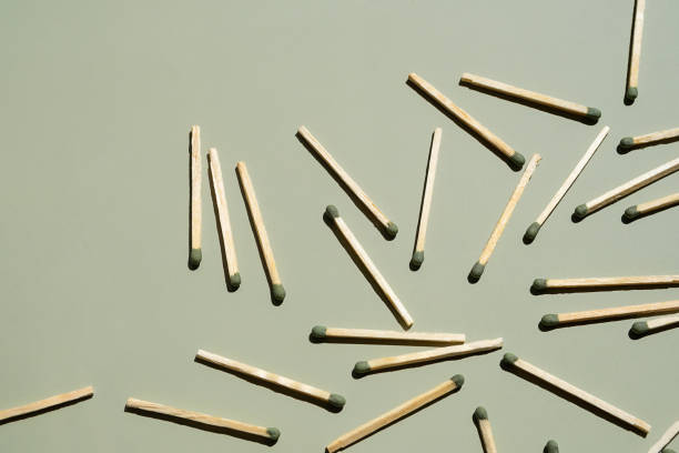 istock Wooden matchsticks with green tips scattered on light green surface. 2168489777