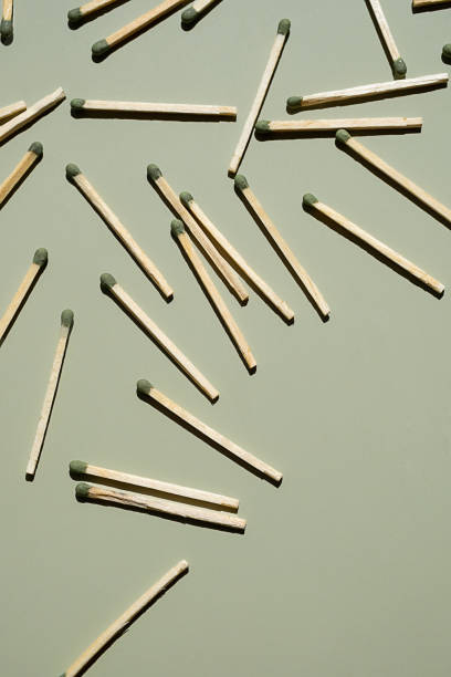 istock Wooden matchsticks with green tips scattered on light green surface. 2168489796