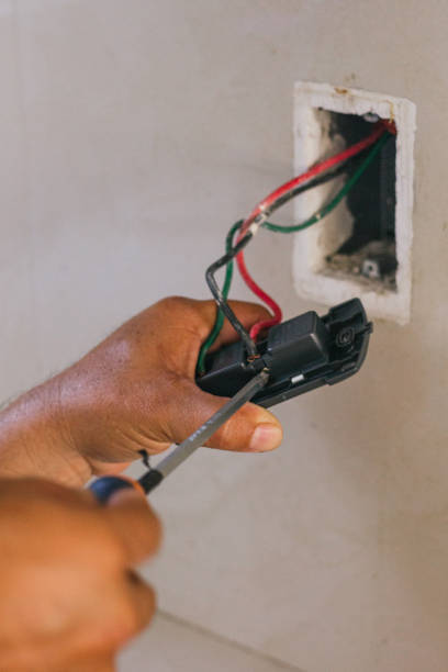 istock Hands of electrician screwing a plate for the socket 2168491708