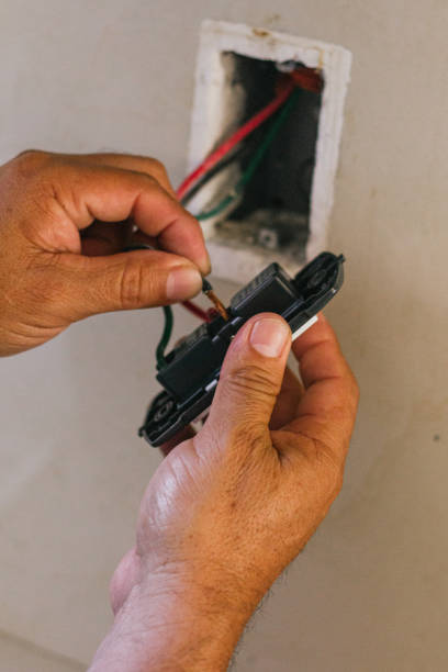 istock Hands of electrician screwing a plate for the socket 2168491767