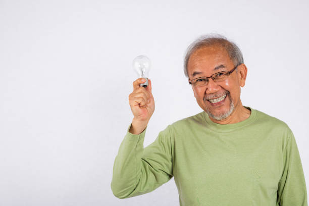 istock Portrait Asian old man is holding light bulb and smiling studio shot isolated on white background. Concept of intelligence and creativity, as the man is holding a symbol of innovation 2168494778