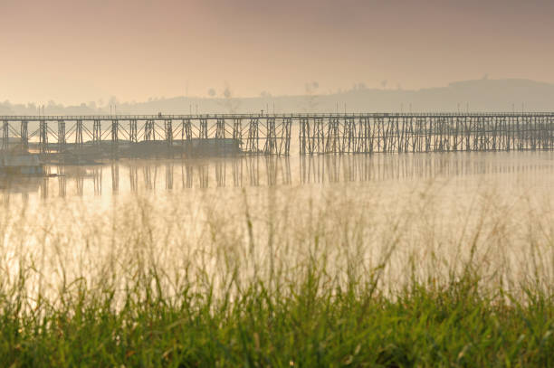 Silhouette of Mon Bridge During the sunrise in winter, see the fog floating at Sangkhlaburi, Kanchanaburi Province, Thailand