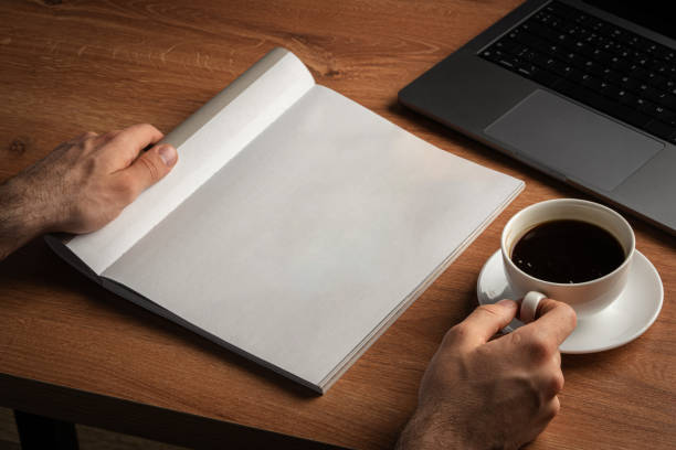 istock Man Reading Page of Magazine While Holding Coffee Cup 2168506430