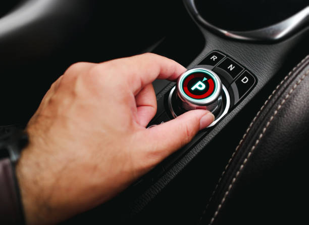 Driver hand turning a rotary gear shift dial on the dashboard of an EV car or electric vehicle , P Parking gear position , electric car technology concept