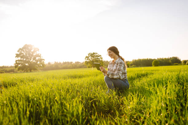 istock A young woman is smiling while kneeling in lush green grass, using a tablet. 2168507601