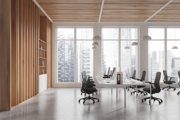 istock Workplace interior with armchairs and desks, pc monitors and shelf near window 2168510993