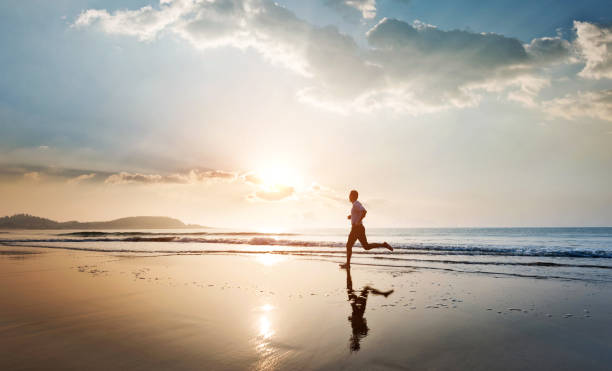 istock Man jogging on the beach at sunset 2168512707