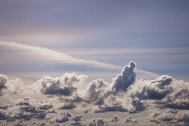 Large silver lined white clouds floating in a brightly lit sunny purple mauve sky.
