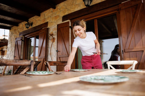 Beautiful young woman setting the table on balcony