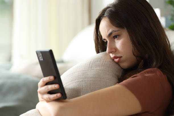 istock Sad woman hugging pillow checking phone 2168514648