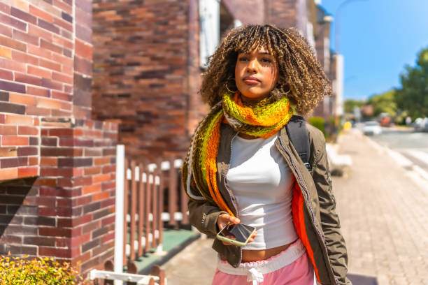 istock Latin beauty woman using phone while walking along street 2168516239