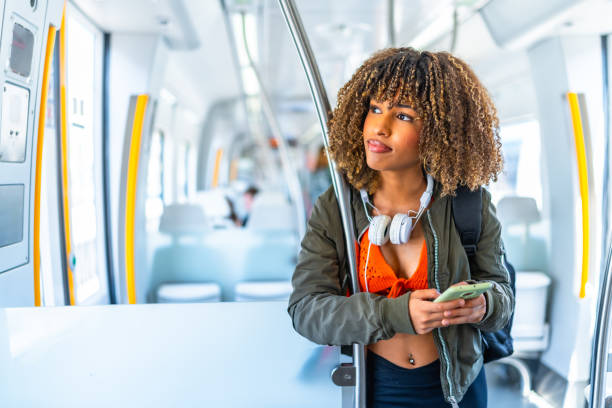 istock Distracted woman looking away while using phone in a metro 2168516344