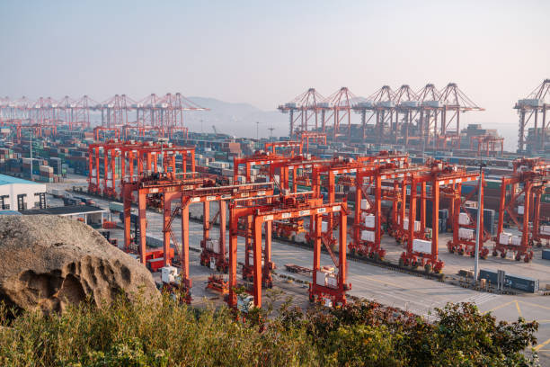 Dynamic view of Shanghai Yangshan deepwater port bustling container port in Shanghai, China, featuring numerous stacked shipping containers and cranes in the commercial harbor.