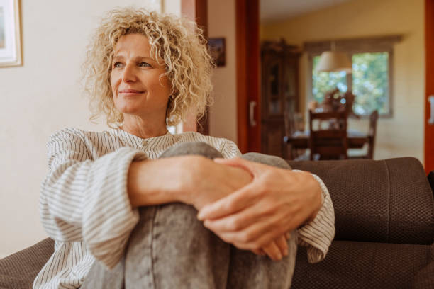 istock Middle aged smiling woman relaxing on couch at home 2168528138