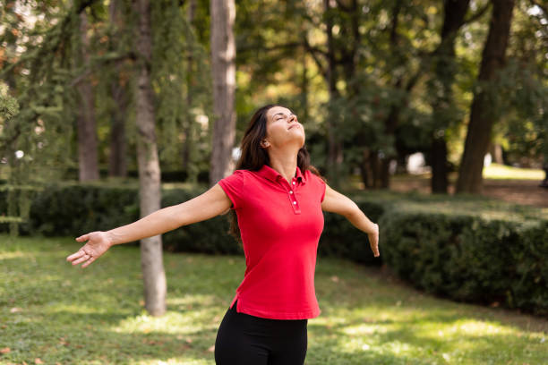 istock Woman standing with open arms in peaceful forest park. 2168529730