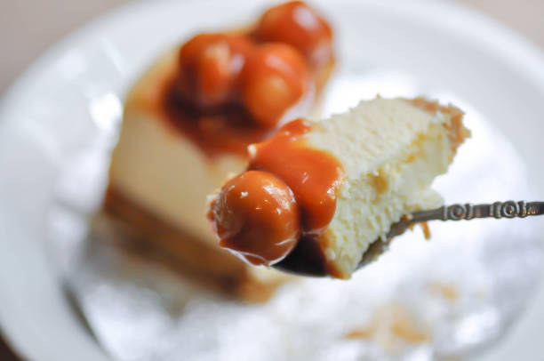 Stock photo showing Indian man holding blackcurrant cheesecake with buttery biscuit base, vanilla mascarpone cream cheese for dessert pudding after restaurant dinner, blurred in background.