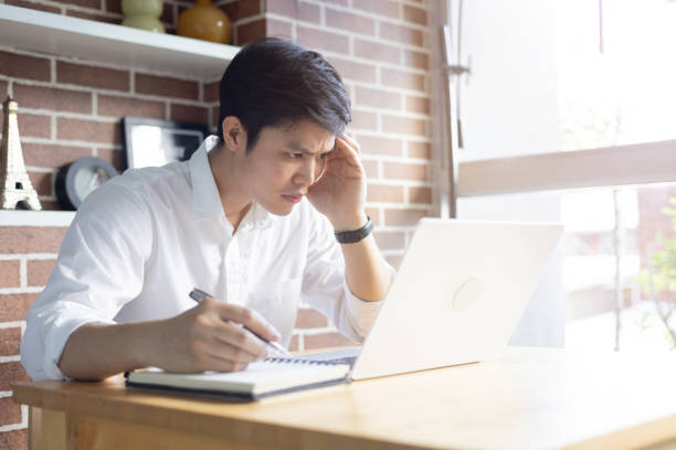 istock close up young asian student man sitting at the library in university and learning online course with frowned on face and worry about lesson for education and lifestyle concept 2168532780