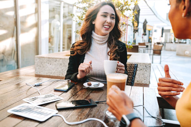 istock Two friends in coffee shop charging cell phone on portable solar panel board 2168546605