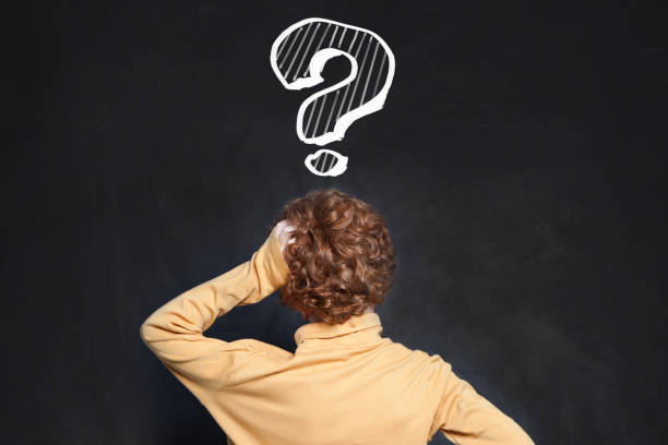 istock Back of young boy school student looking at question mark on blackboard. Idea and Education concept 2168549528