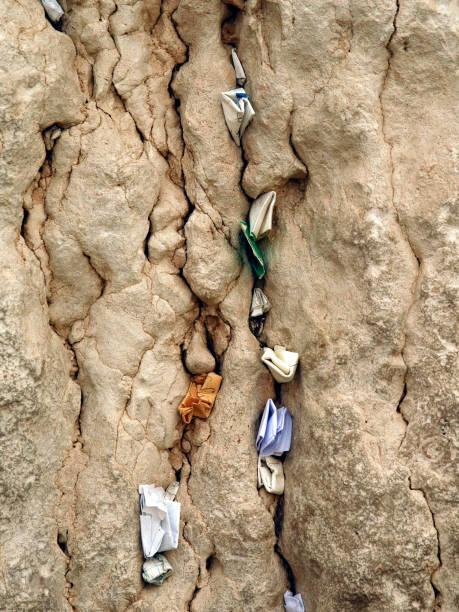 Numerous tiny, folded pieces of colored paper with written notes addressed to God are crammed into cracks, crevices and crannies of the Western Wall in the Old City of Jerusalem. stock photo