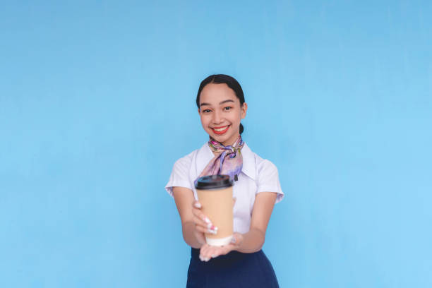 istock A flight attendant holding a cup on her left hand. A stewardess serving coffee to passengers. Center. 2168571809