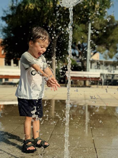 3 years boy plays with a water in a city park