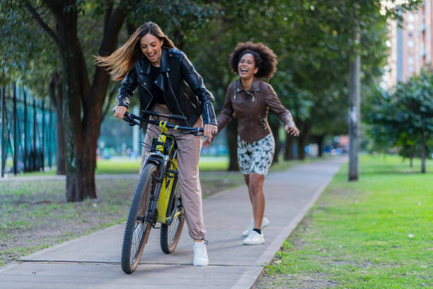 Latina friends from Bogota Colombia, between 29 and 34 years old, laugh while walking in front of a beautiful sunset in the park wearing sports clothes