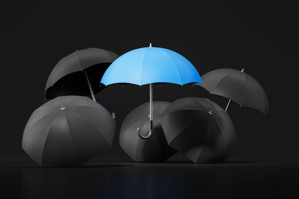 Blue umbrella among black on dark background, stand out of the crowd and being different. Concept of leadership or uniqueness. 3D rendering illustration