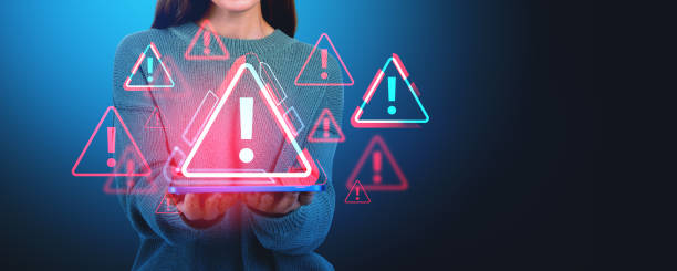 istock Woman holding a tablet with floating warning symbols, digital ar 2168581273