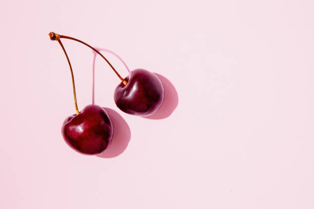 istock Pair of cherries with stem on a pink background 2168584761