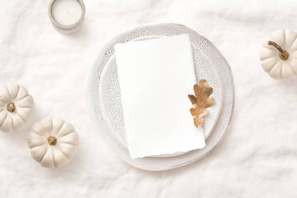 bright elegant menu or invitation card mockup with festive autumn / fall themed table setting with white pumpkins, candle and natural leaf, ideal for thanksgiving or seasonal weddings - flat lay
