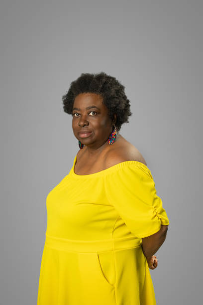 istock Woman posing for a studio portrait wearing yellow top with a gray background 2168593849