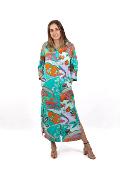 istock A young woman stands in a full-length image, wearing a brightly colored and bold patterned shirt dress against a crisp white background 2168595327