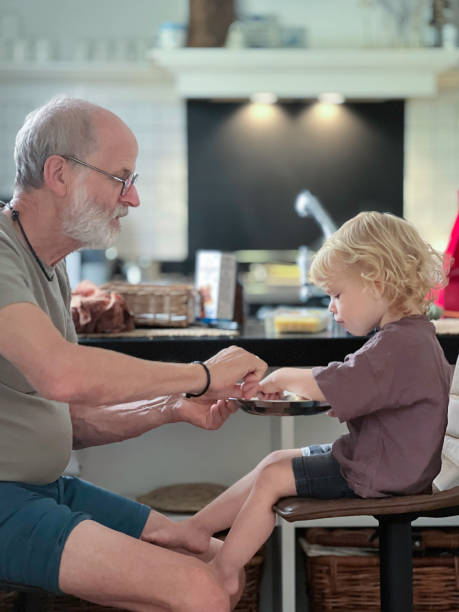 istock Granddad assisting Feeding his Toddler Grandson. 2168595452