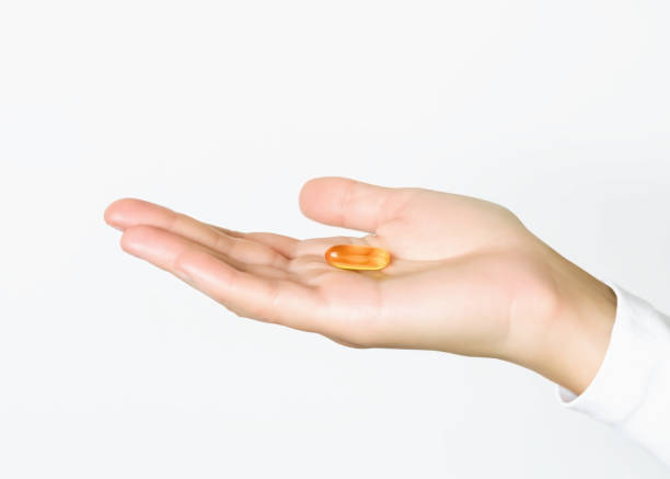 istock woman holding yellow capsule pill in her palm 2168596913