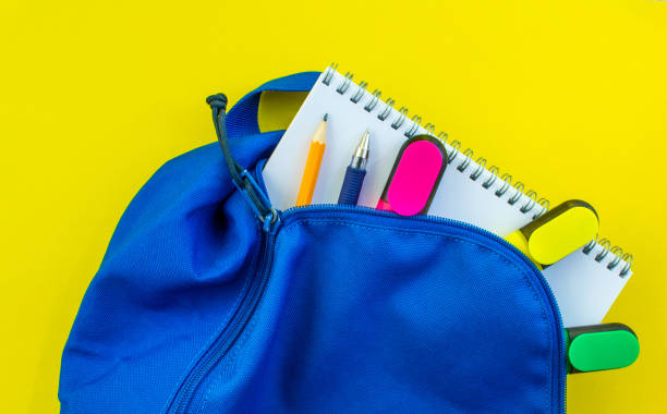 istock School backpack, pencil, pen, markers, and notepad on a yellow background. 2168602288