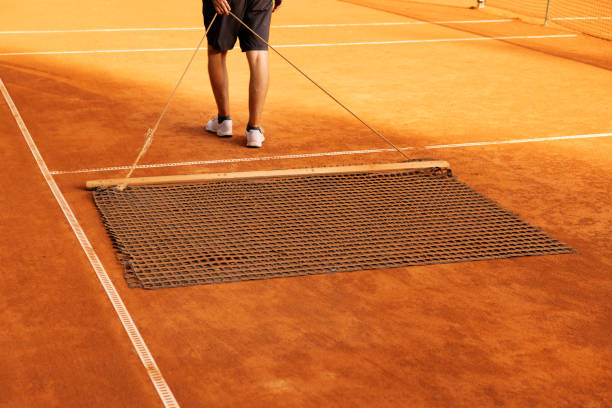 man clean clay tennis court. levelling the surface