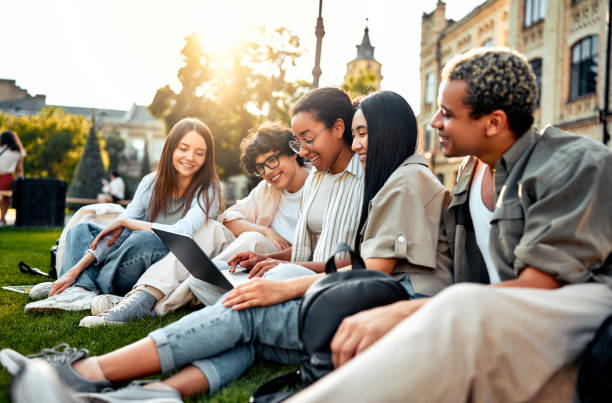 istock University students are sitting on the grass with a laptop and preparing for classes. Students relax on the campus. 2168604831