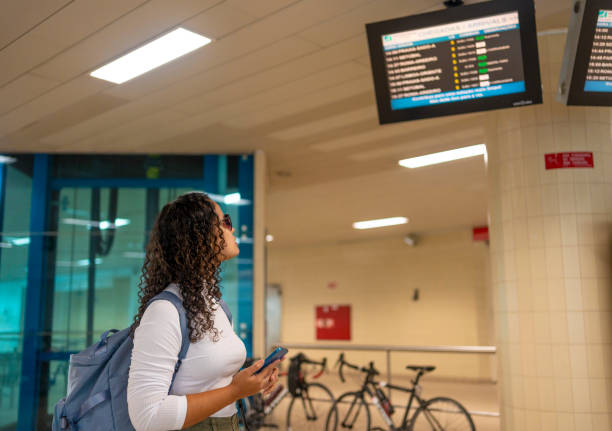 istock Woman at train station looking at information board 2168619495
