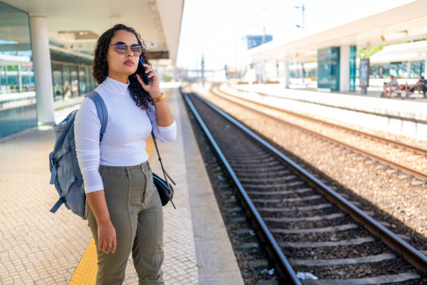istock Woman with cell phone at train station 2168619504
