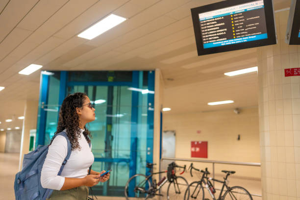 istock Woman at train station looking at information board 2168619556