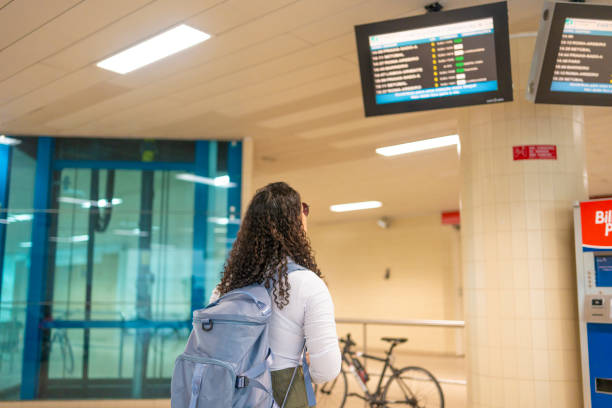 istock Woman at train station looking at information board 2168619603