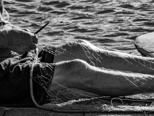 An old fisherman mends his nets