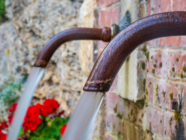 many steel taps with drinking water flowing in college bathroom