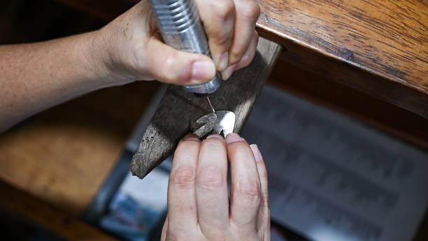 istock Goldsmith engraving silver plate with electric tool on wooden table 2168620806