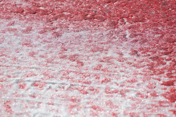 Reflective glitter on asphalt at a pedestrian crossing. Red and white abstract background.